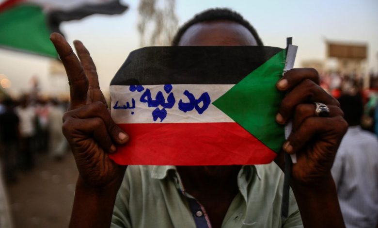 متظاهر سوداني يحمل علم البلاد مكتوب عليه "مدنية بس" خلال تظاهرة أمام القيادة المركزية للجيش، الخرطوم، 2 مايو 2019. وكالة الأنباء الفرنسية.