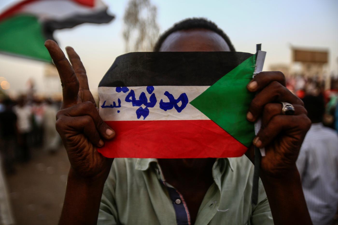 متظاهر سوداني يحمل علم البلاد مكتوب عليه "مدنية بس" خلال تظاهرة أمام القيادة المركزية للجيش، الخرطوم، 2 مايو 2019. وكالة الأنباء الفرنسية.