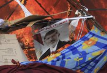 A poster of ُEgypt's former president Mohamed Morsi reads "Yes to legitimacy" as riot police clears the area of members of the Muslim Brotherhood and supporters at Rabaa Adawiya square, where they were camping, hundreds of them were killed on that single event, Cairo, 14 August 2013. Reuters, Stringer.