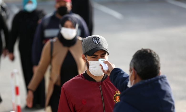 A security guard measures the temperature of workers in line in a factory in Manouba after the announcement of total containment on 22 March 2020 against the pandemic of CoViD-19, Tunisia, 14 April 2020. Reuters, Mohamed Krit.