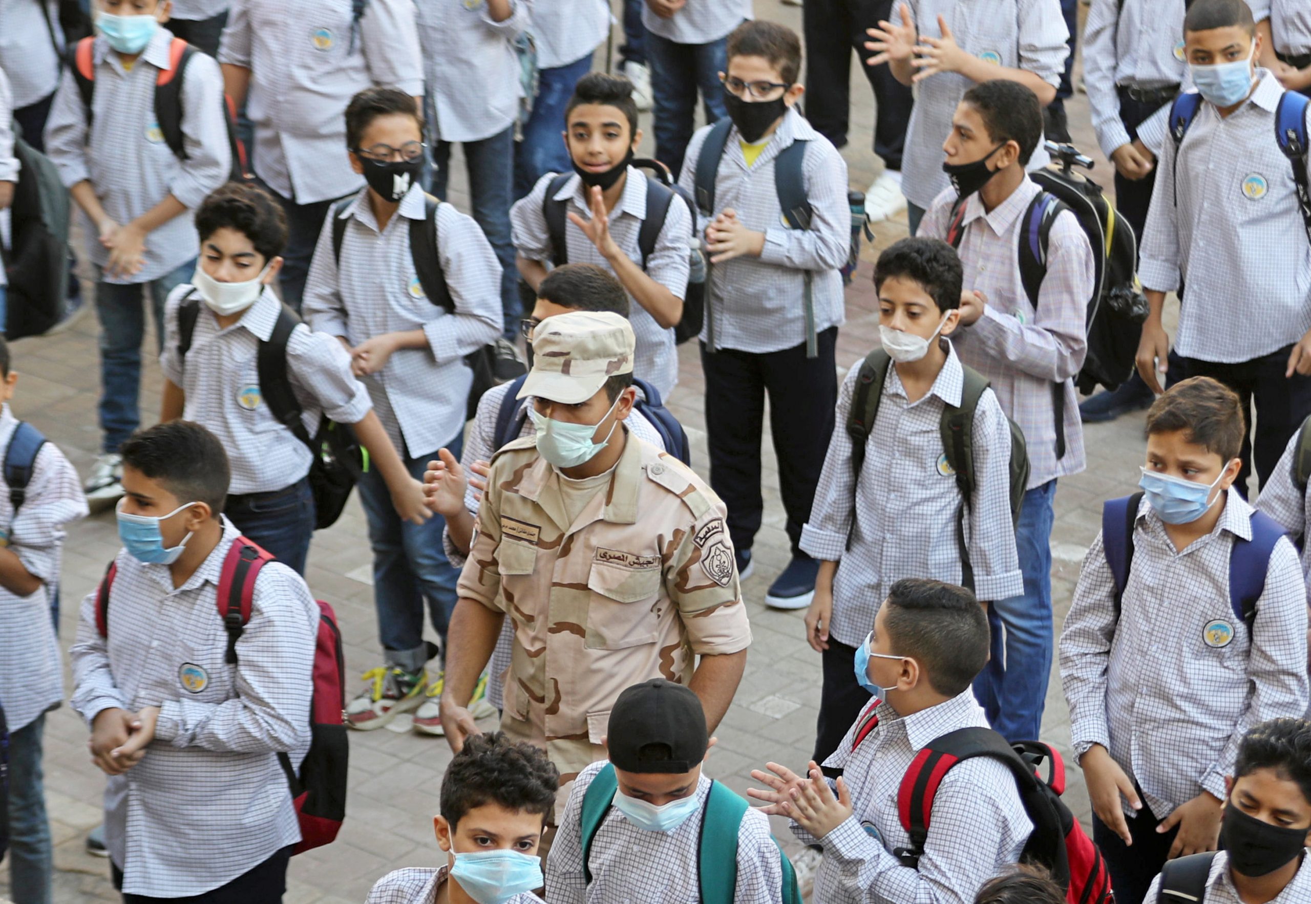 An army member wearing a protective mask stands guard between students as they attend the first day at Al Saadeya school, following months of closure due to the Covid-19 outbreak, Cairo, Egypt, 17 October 2020. Reuters, Mohamed Abd El Ghany.