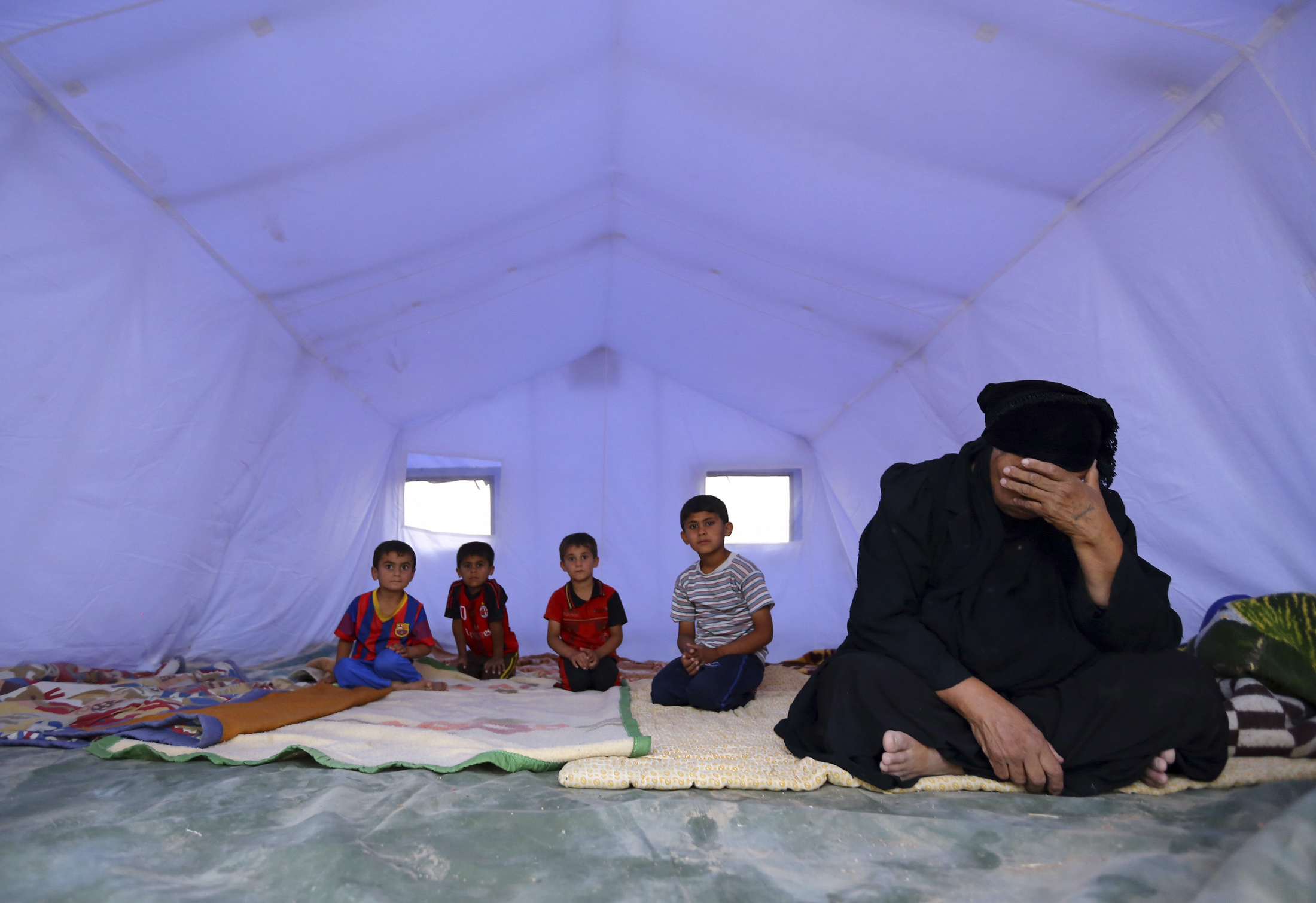 أسرة عراقية هاربة من العنف بالموصل عقب سقوط المدينة بيد داعش، تجلس داخل خيمة بمركز إيواء على مشارف مدينة أربيل بكردستان العراق، 12 يونيو 2014. روبترز، صحفي محلي.