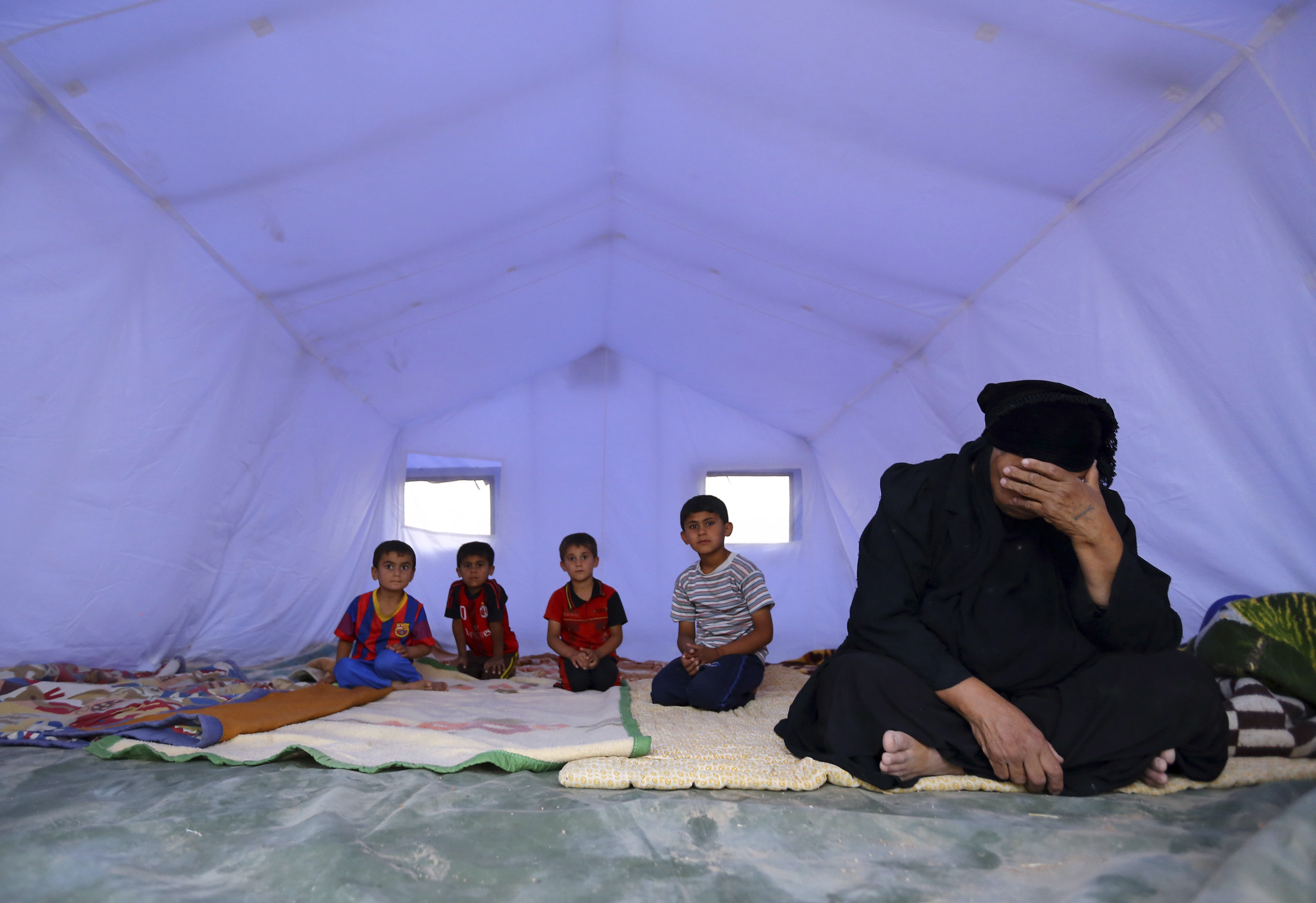 An Iraqi family, which fled from the violence in Mosul following the city’s fall to ISIL, sits inside a tent at a camp on the outskirts of Arbil in Iraq's Kurdistan region, 12 June 2014. Reuters, stringer.