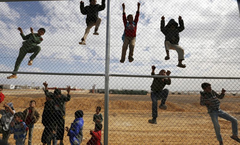 أطفال سوريون لاجئون يتسلقون على سياج من أجل مشاهدة ورشة تدريبية لكرة القدم بمخيم الأزرق للاجئين، الأردن، 17 نوفمبر 2015. رويترز، محمد حامد.