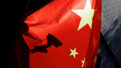 A surveillance camera is silhouetted behind a Chinese national flag in Beijing, China, 3 November 2022. REUTERS/Thomas Peter.