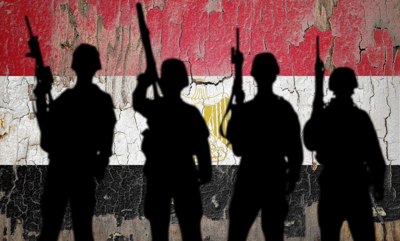 Silhouettes of soldiers standing against a weathered Egyptian flag backdrop, 13 March, 2024. Source: Zmotions via Shutterstock.