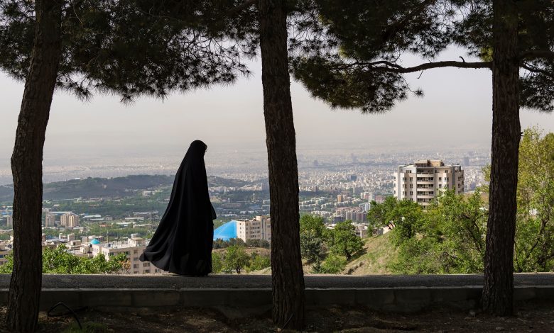امرأة محجبة تسير وخلفها مشهد لمدينة طهران، 10 مايو 2018. المصدر: آرتوغرافي عبر شاترستوك.