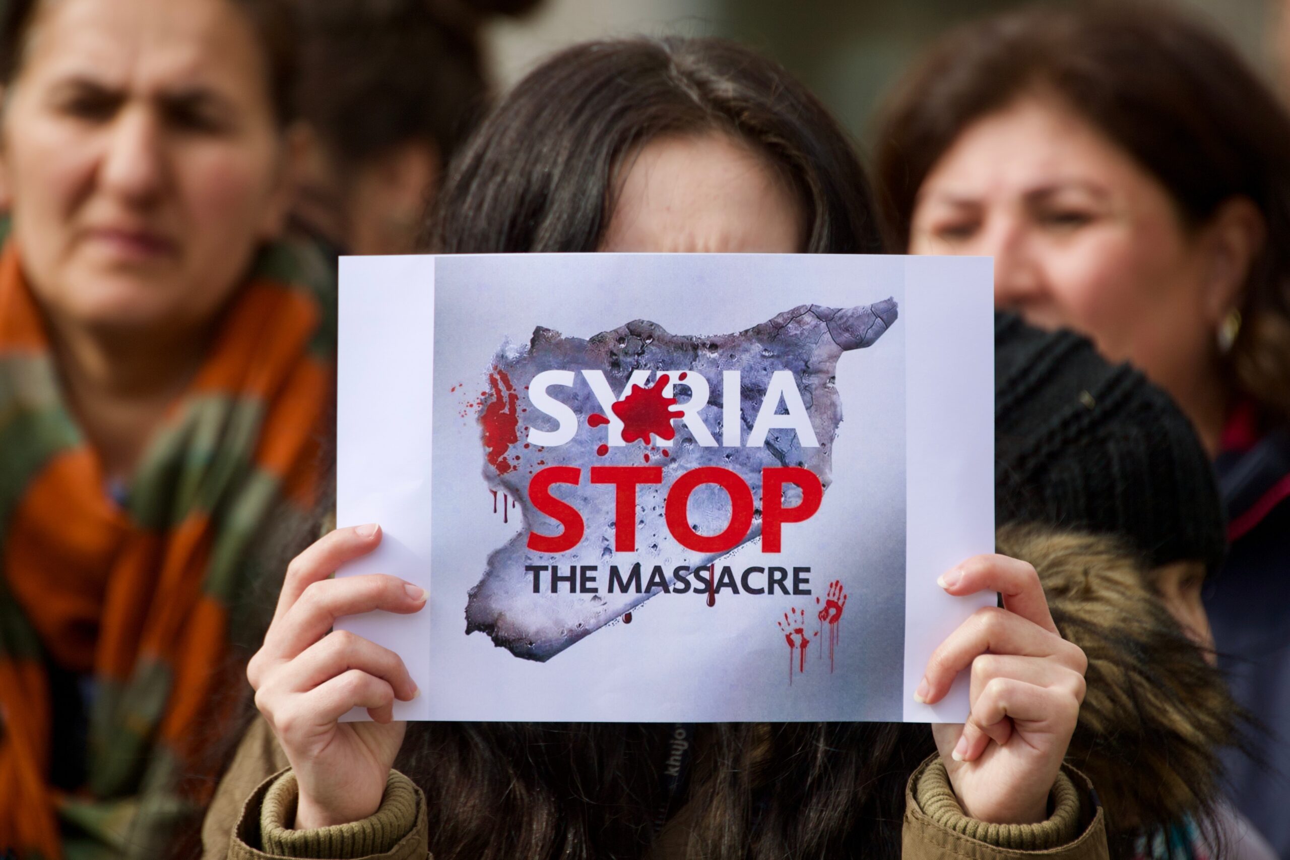 Image of a slogan displayed during a protest in Frankfurt, Germany, against the massacre of Alawites in Syria, 15 March 2025. Source: Ryan Nash Photography via Shutterstock.